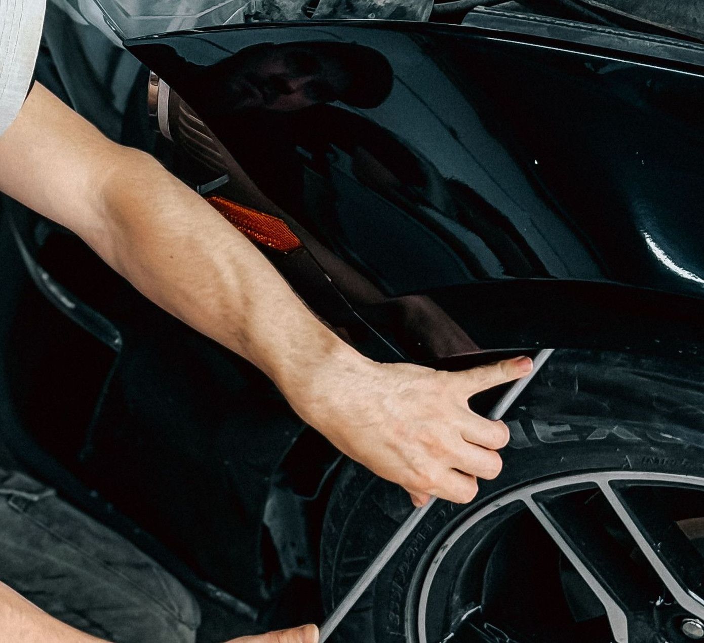 Mechanic working meticulously on a car bumper repair inside an auto garage.